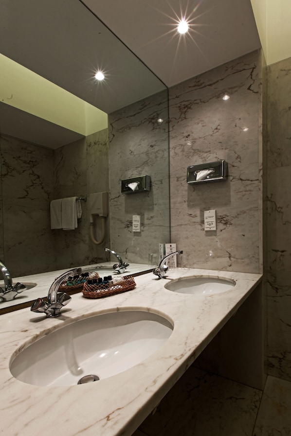 A modern bathroom with two sinks, a large mirror, and a towel rack.