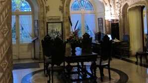 An ornate lobby with a round table and chairs, arched windows, and intricate ceiling details. - Bussaco Palace Hotel (Mealhada)