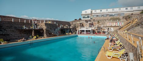 Een seizoensgebonden buitenzwembad en ligstoelen