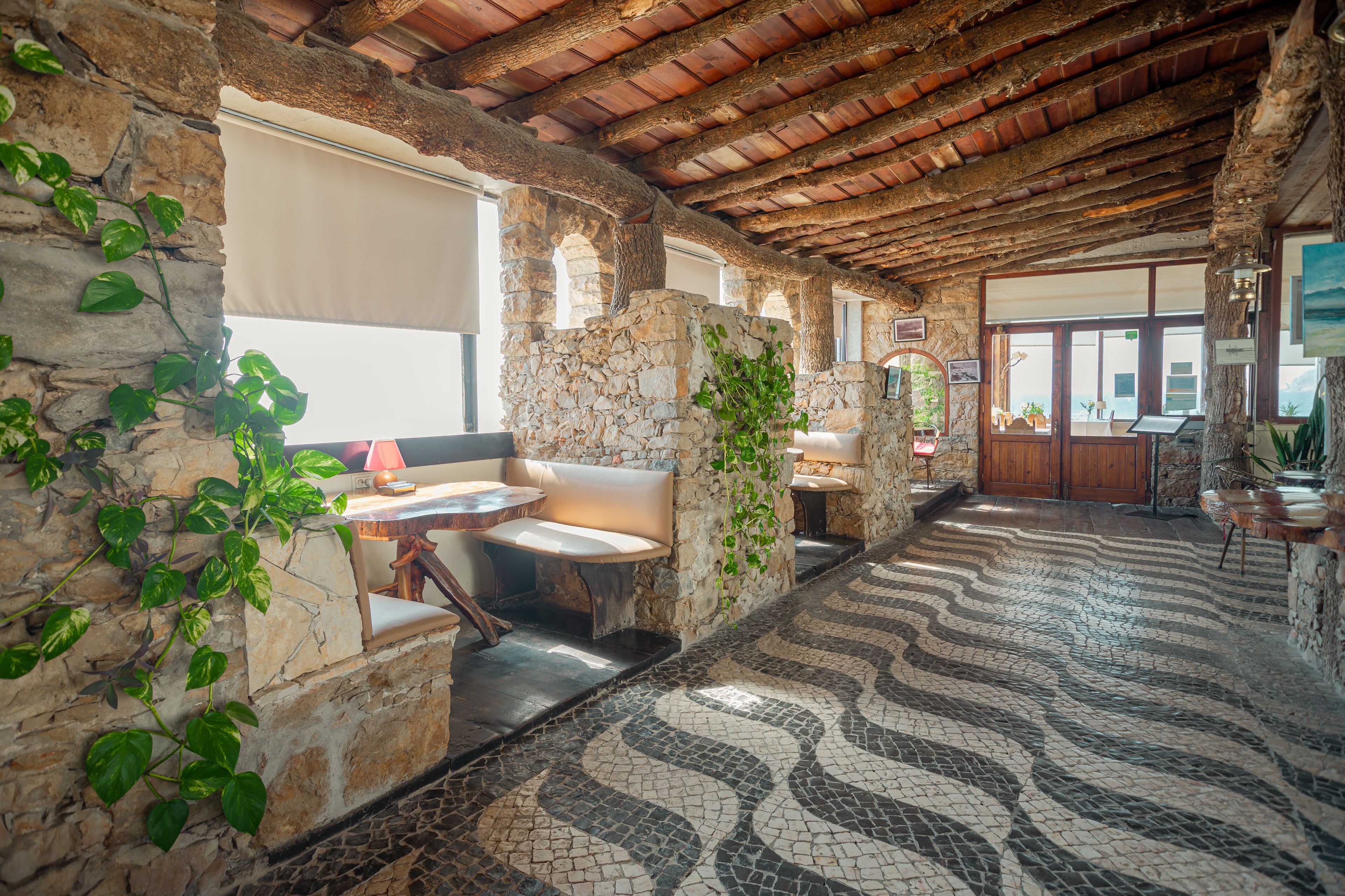 A stone-walled interior with a tiled floor, stone benches, and a wooden ceiling.