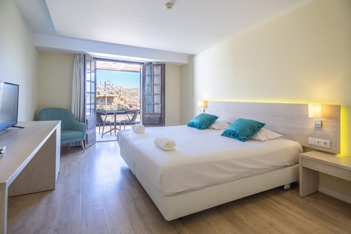 Une chambre d’hôtel avec un lit, un bureau, une chaise et une vue sur l’extérieur.
