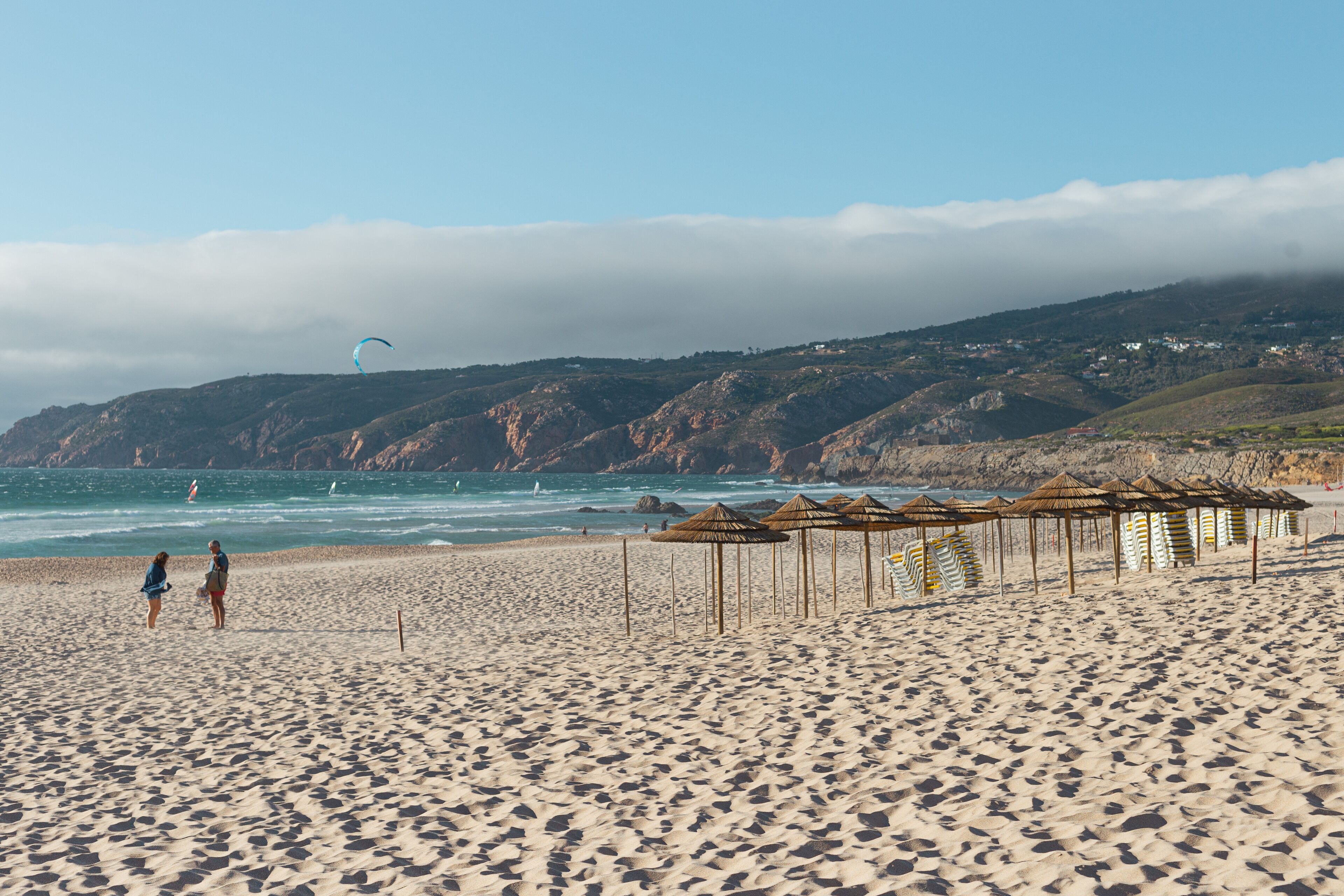 A beach with umbrellas and a person walking.
