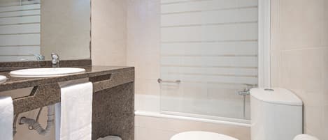 Un baño moderno con lavamanos, inodoro y ducha con mampara de vidrio.