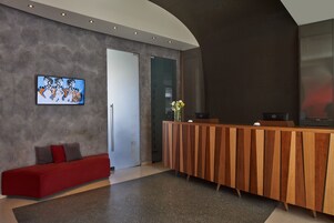Una zona de recepción moderna con un mostrador de madera, un sofá rojo y un cuadro abstracto grande en la pared.