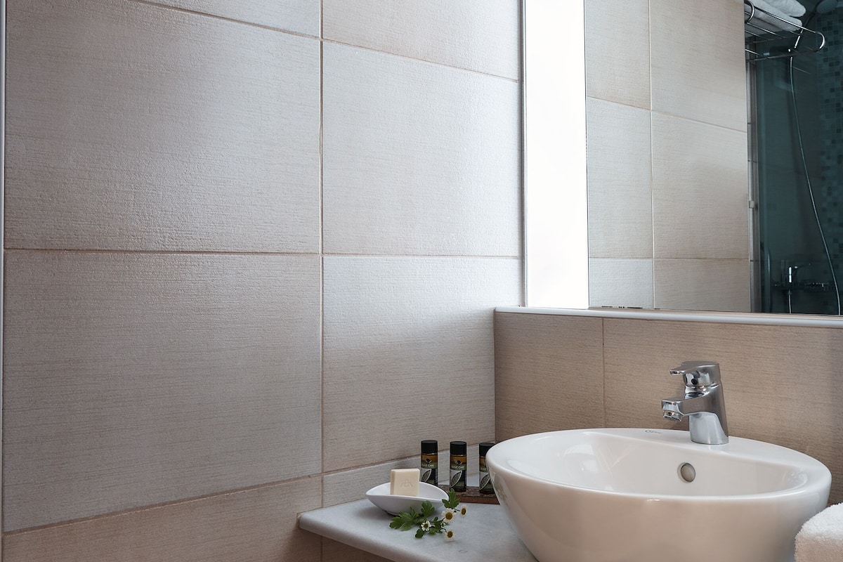 Un baño moderno con un espejo grande, un lavabo redondo y una zona de ducha.