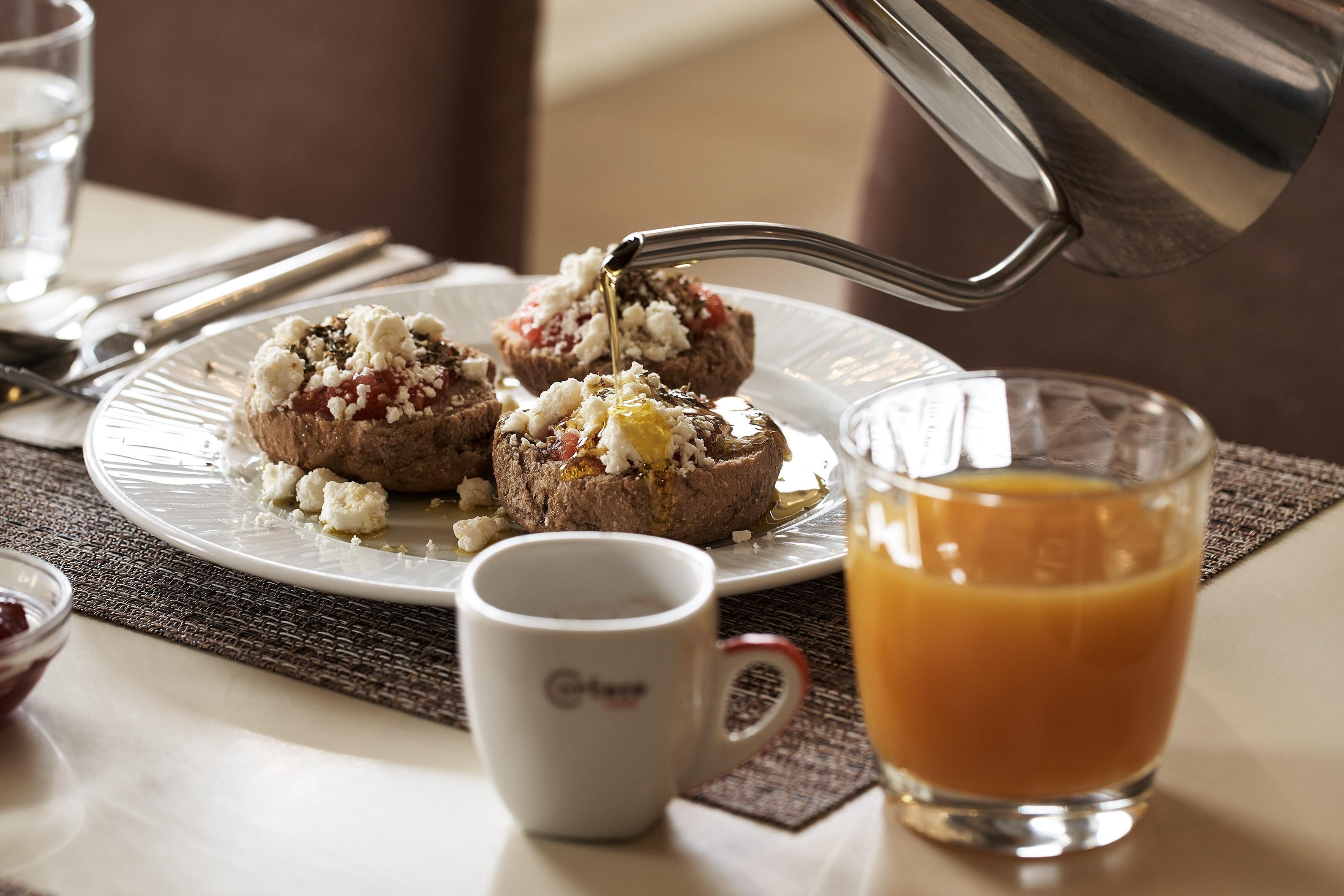 A breakfast setting with a plate of food, a glass of orange juice, and a coffee cup.