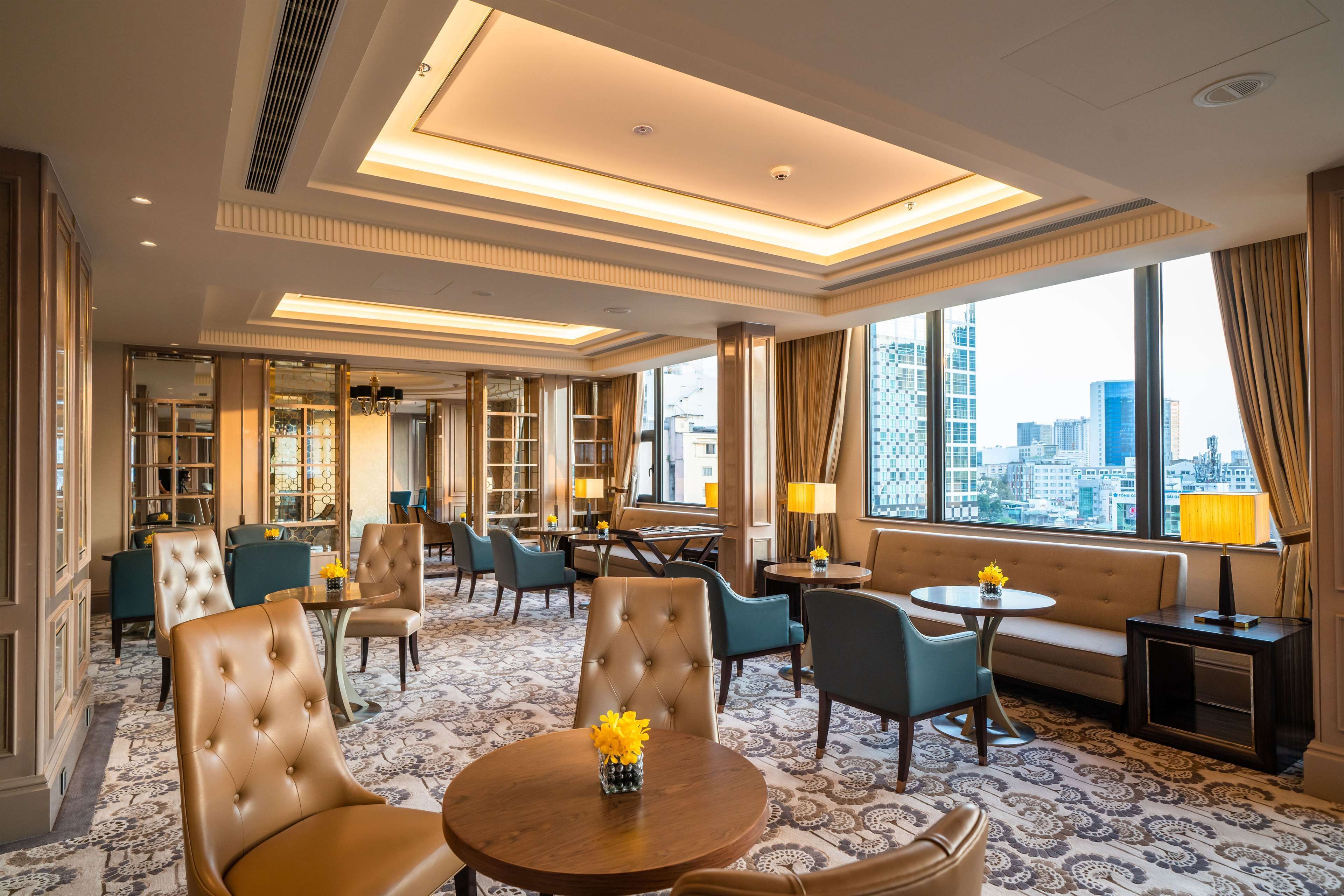 Et hotel lobby med et stort vindue, siddeområde og udsigt over byen.