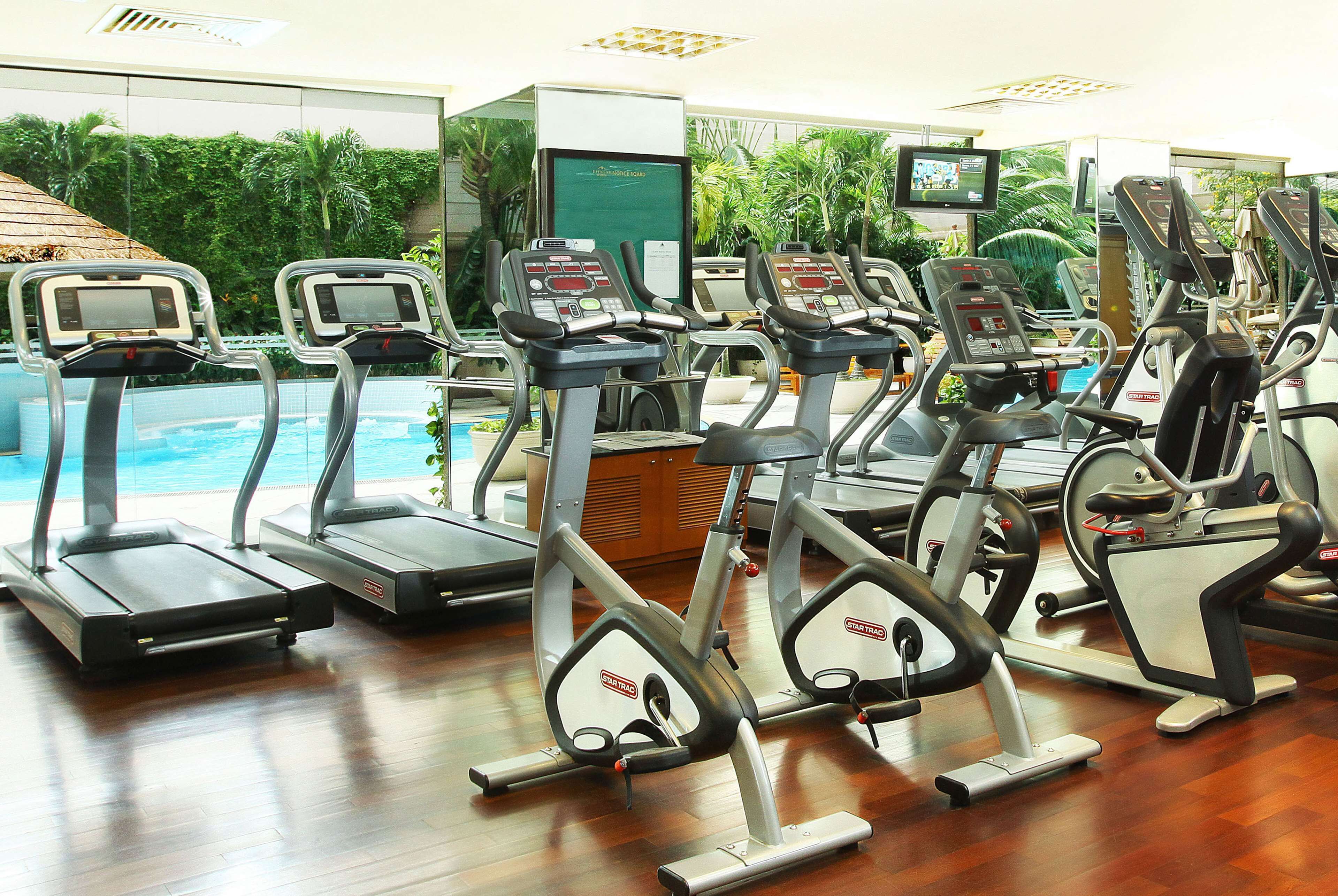 A gym with treadmills, a pool, and a view of greenery.