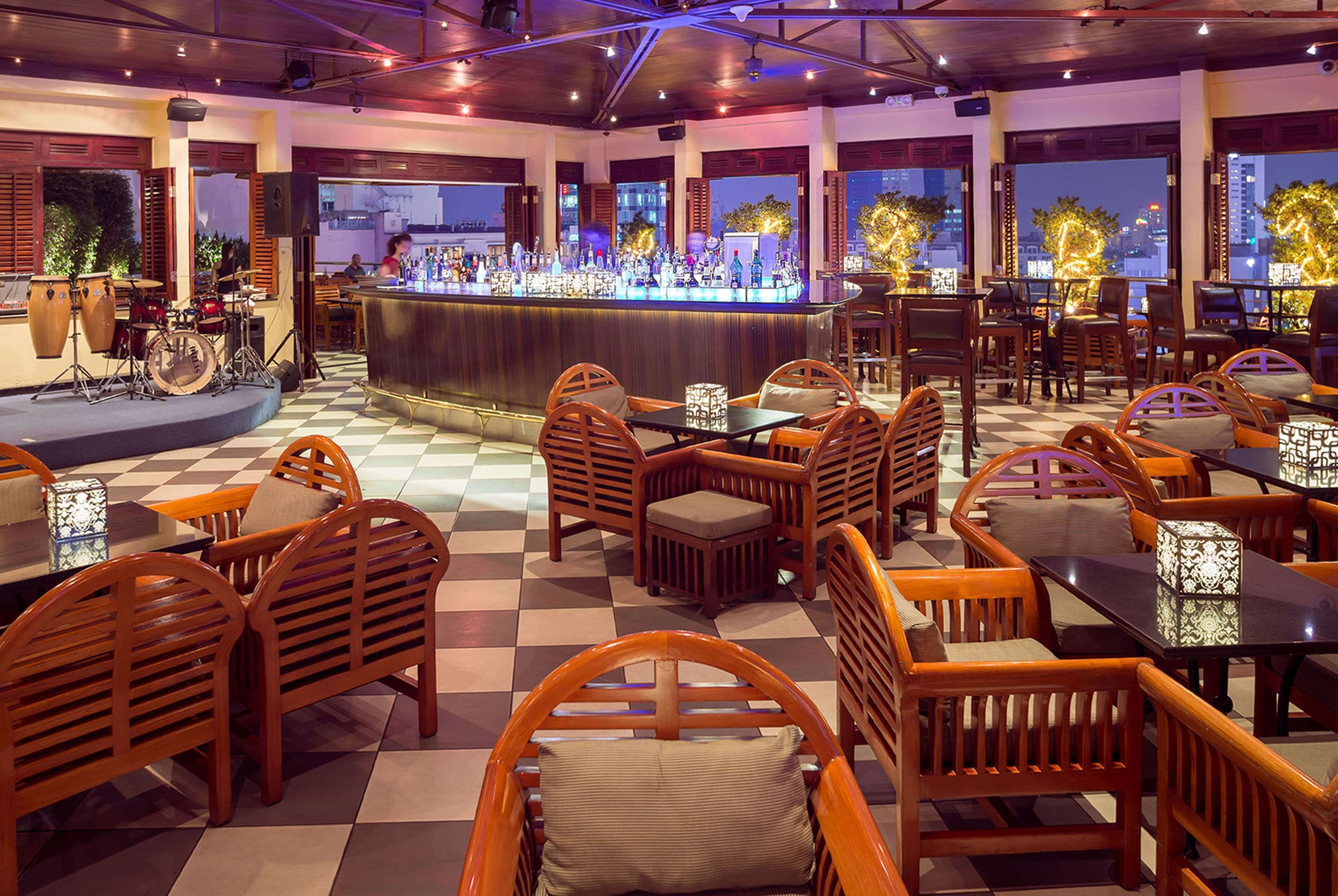 A restaurant with a bar, wooden furniture, and large windows.