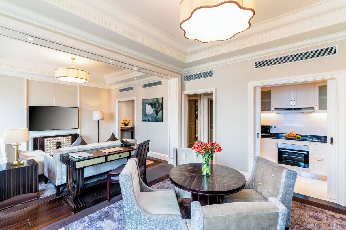 Quarto de hotel moderno com área de jantar, televisão de tela plana, lareira e cozinha.