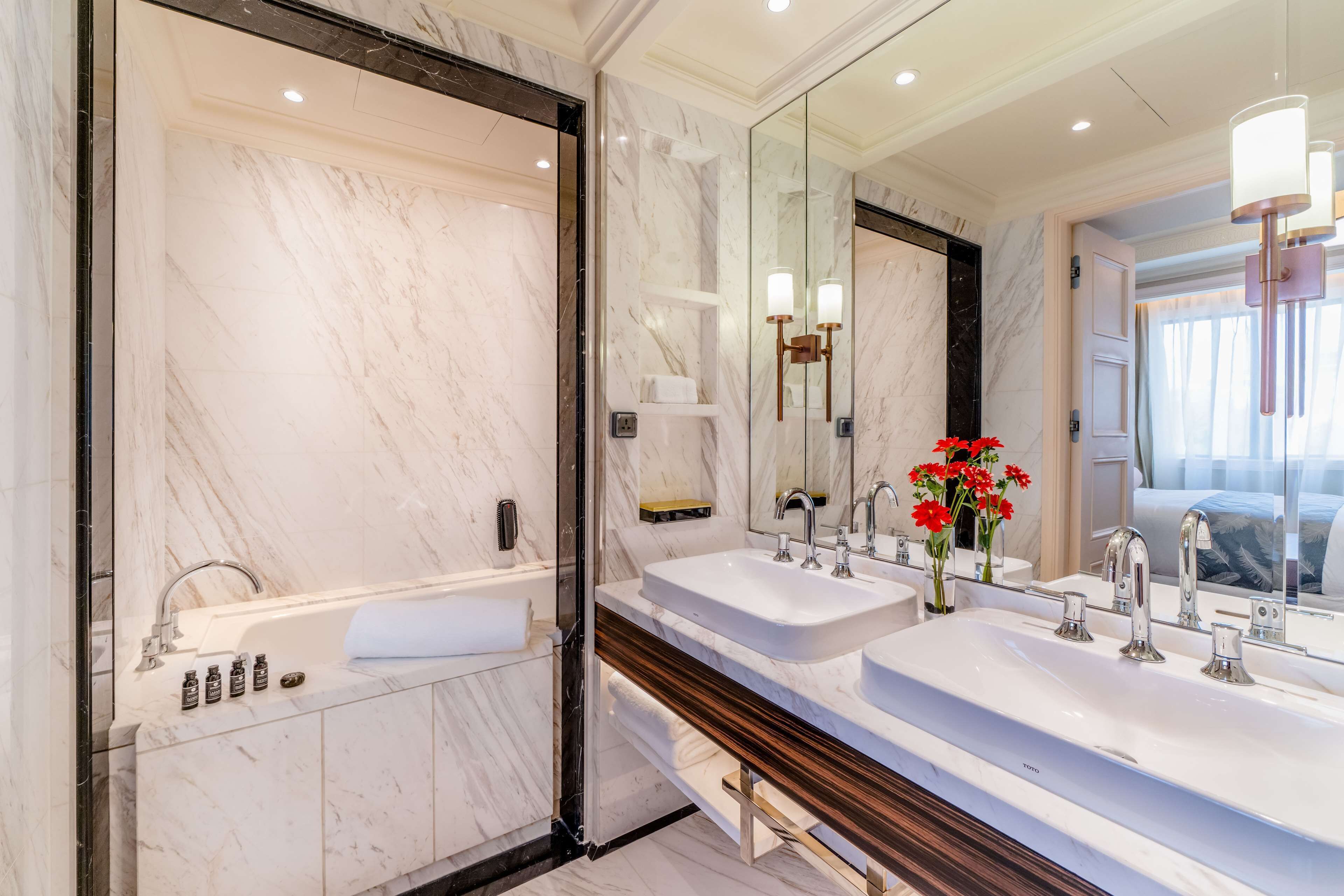 A modern bathroom with a large mirror, two sinks, a bathtub, and a shower.