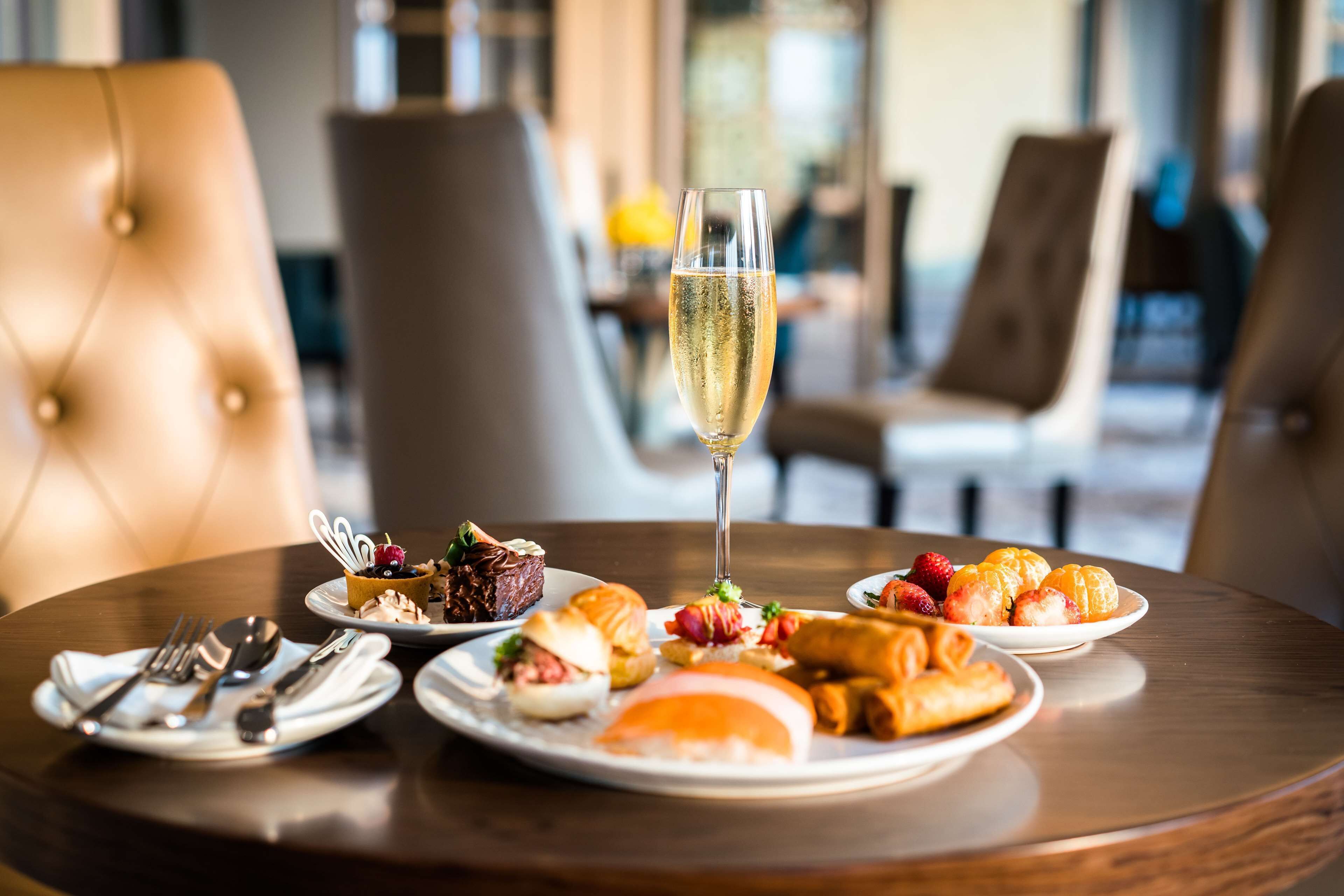 A dining table with plates of food and a glass of champagne.