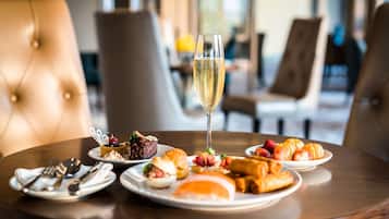 A dining table with plates of food and a glass of champagne.