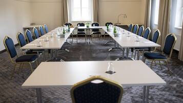Un salón de conferencias con una larga mesa, sillas y suelo alfombrado.