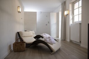 Un cuarto de spa con una camilla de masaje, una cesta de mimbre y una zona de ducha.