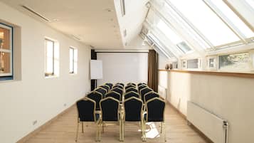 A conference room with a long table and chairs, large windows, and a whiteboard.