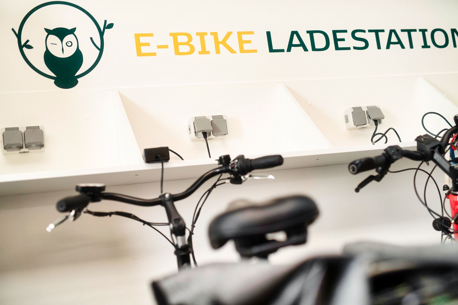 Una estación de bicicletas eléctricas con varios puntos de carga y un logotipo de un búho.