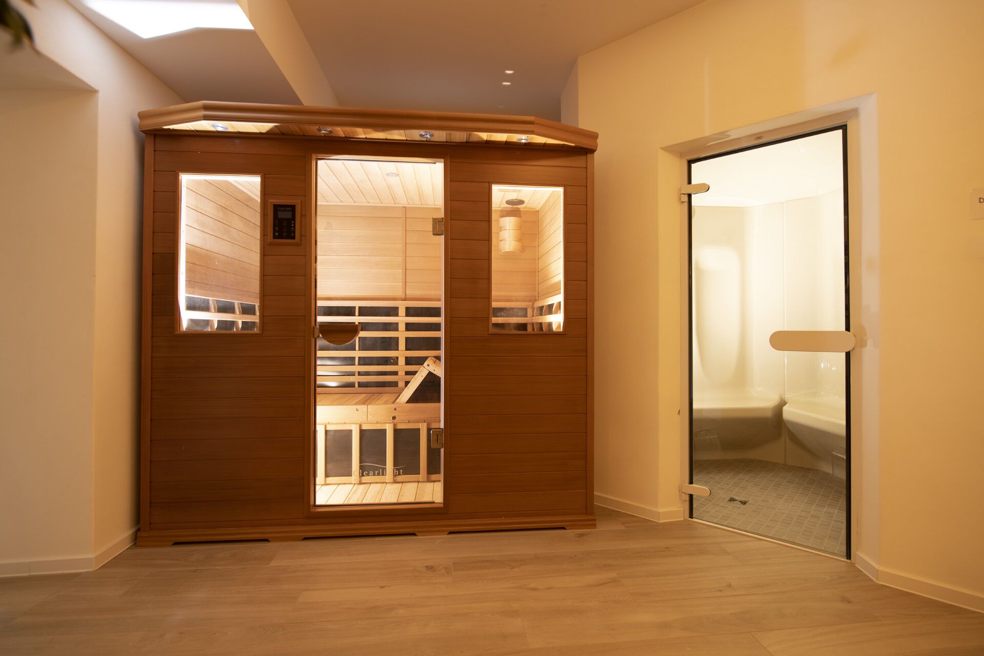 A sauna room with wooden walls and a glass door leading to a shower area.