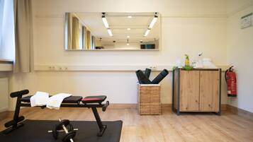 A gym with exercise equipment, a mirror, a wooden cabinet, and a fire extinguisher.