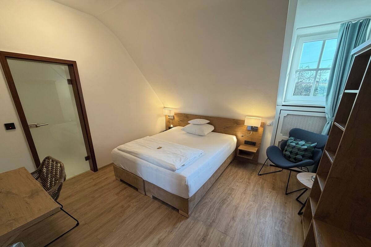 Une chambre bien rangée, avec un lit, des tables de chevet, une chaise et une fenêtre.
