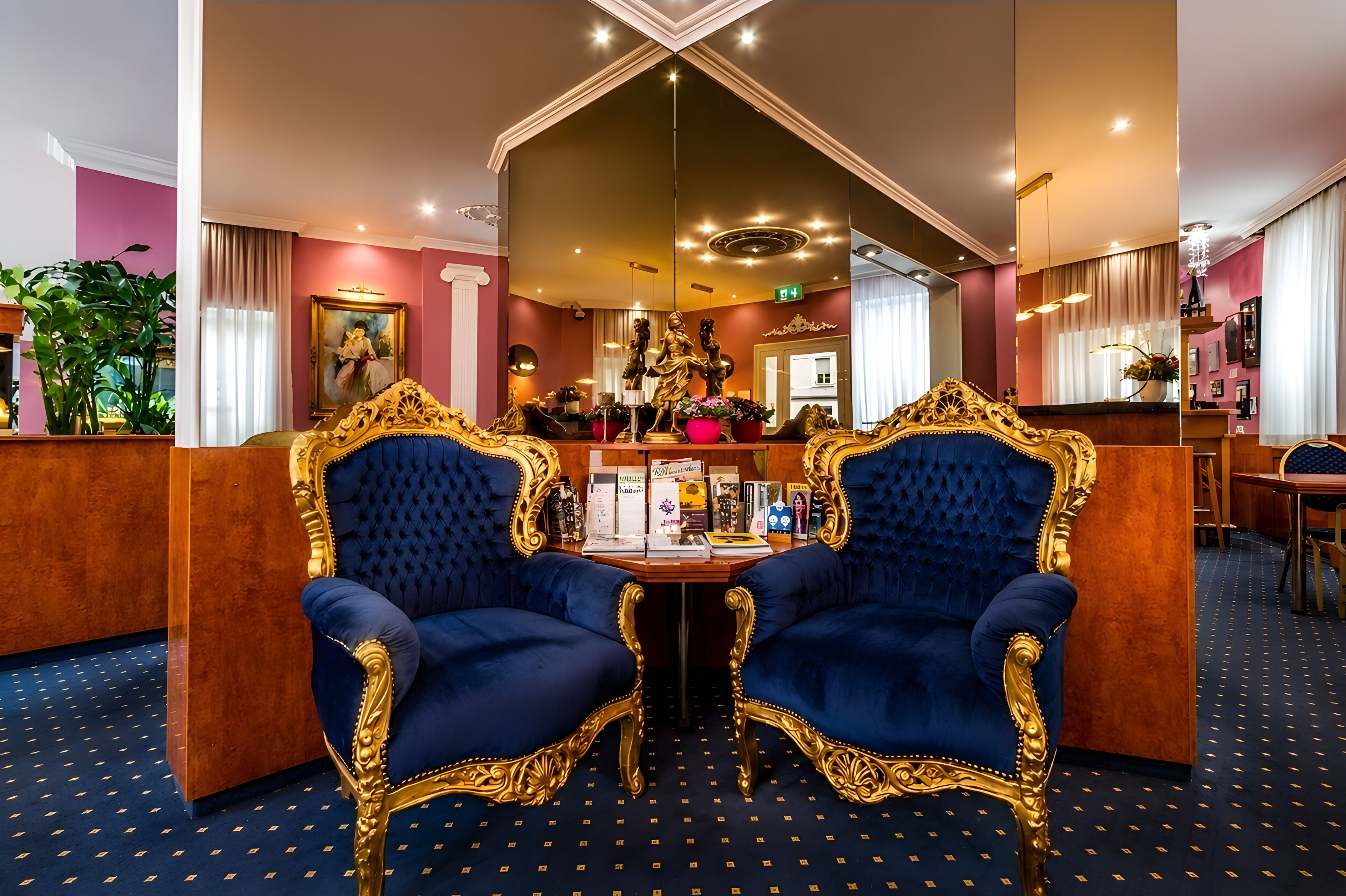 Ein Zimmer mit zwei verzierten blauen Stühlen, einem Holztisch und einem Spiegel, der den Raum widerspiegelt.