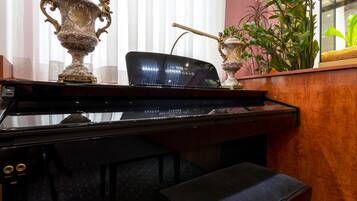 Een piano met een spiegelend oppervlak, een bank en decoratieve vazen.