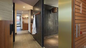 A modern bathroom with a shower, a towel rack, and a wooden panel wall.