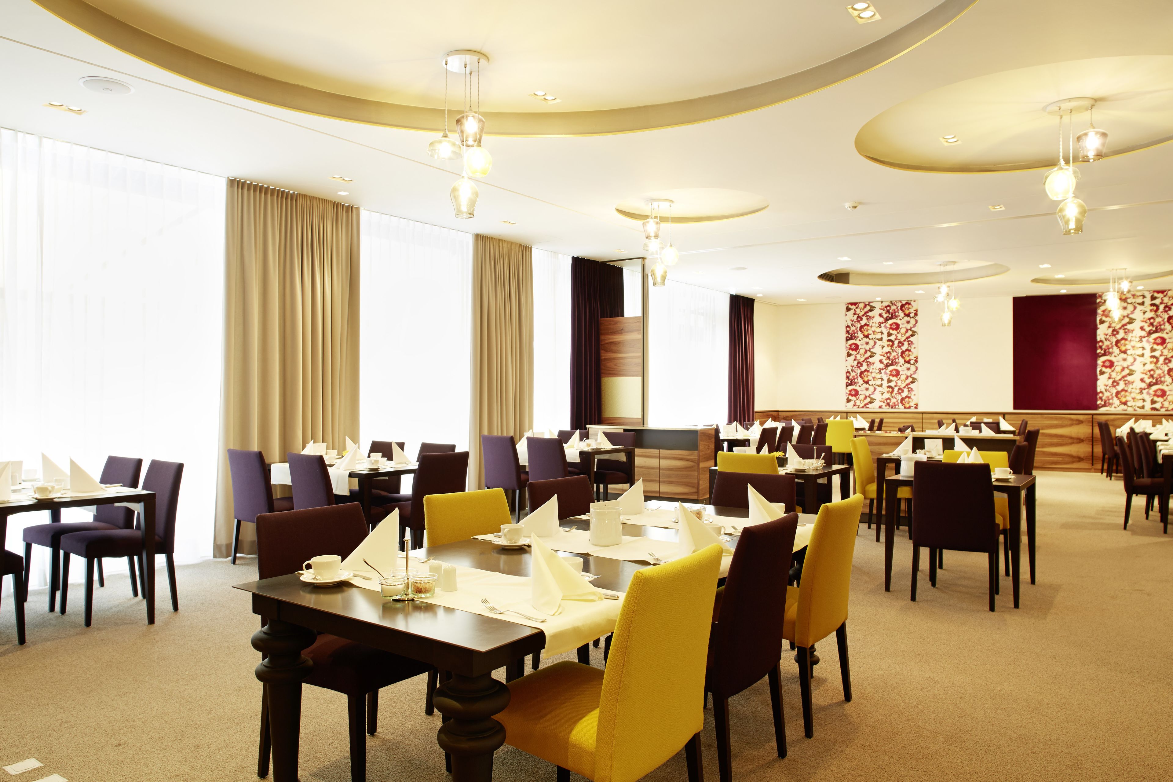 Un comedor de hotel con varias mesas y sillas, dispuesto en un espacio amplio.