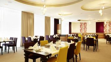 Un comedor de hotel con varias mesas y sillas, dispuesto en un espacio amplio.