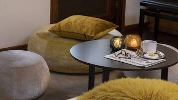 Ein gemütliches Zimmer mit einem Klavier, einer Statue und einem kleinen Tisch mit Tasse und Gläsern.