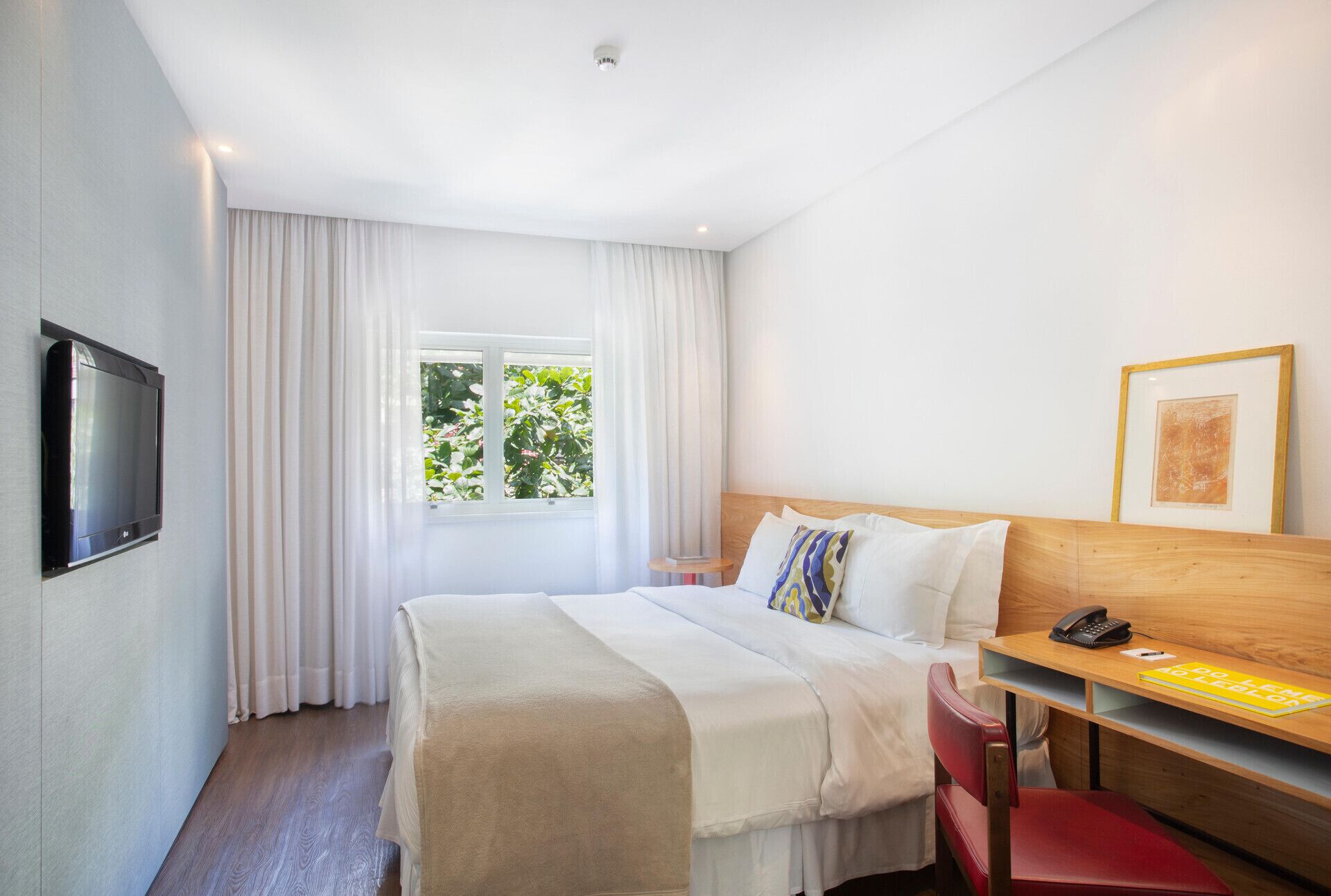 Une chambre d’hôtel équipée d’un lit, d’un bureau, d’un téléphone et d’une télévision.