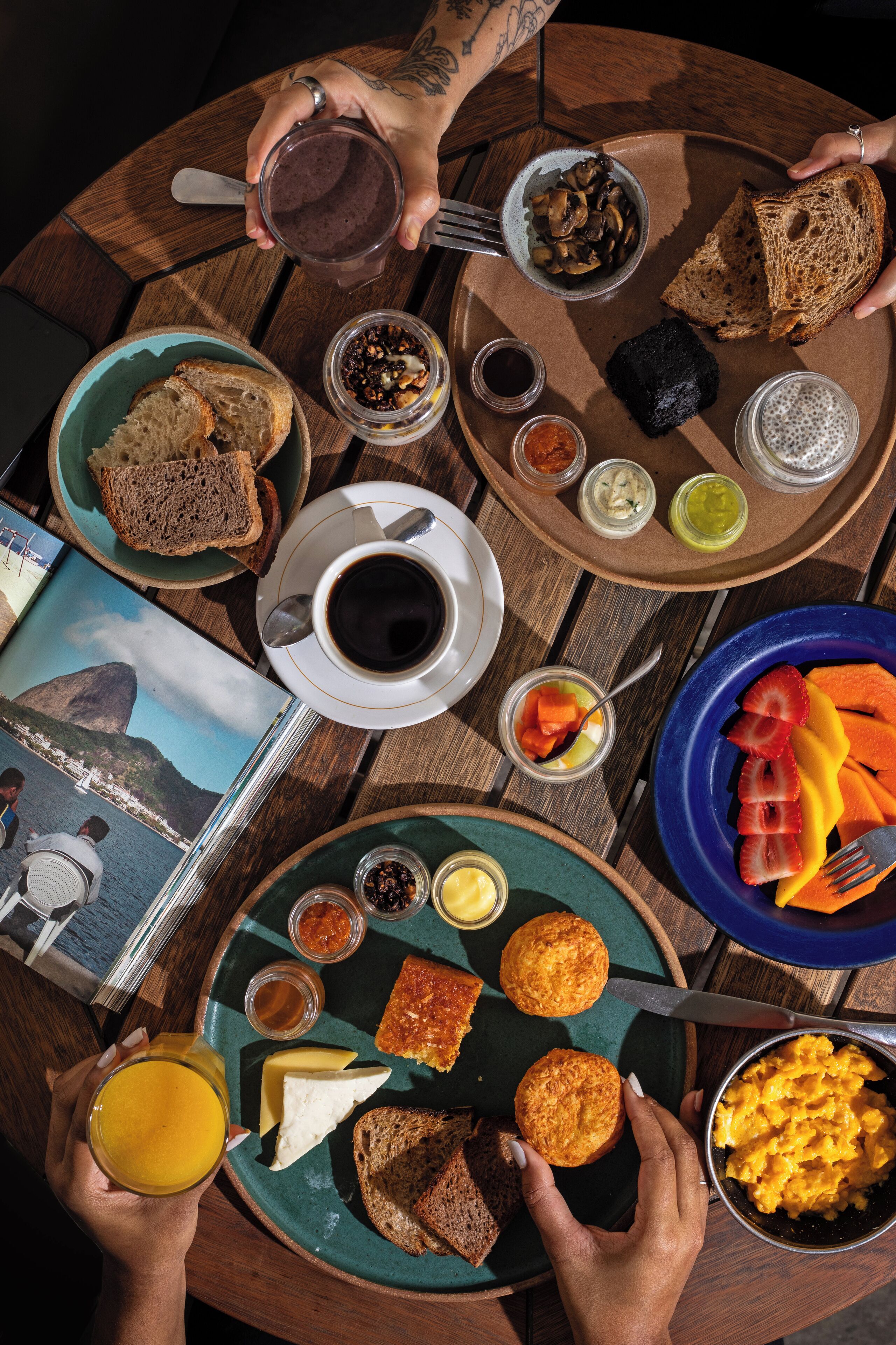 A round wooden table with breakfast items including toast, fruit, eggs, and beverages.