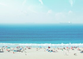 Una playa cerca, sombrillas, toallas de playa, vóleibol de playa