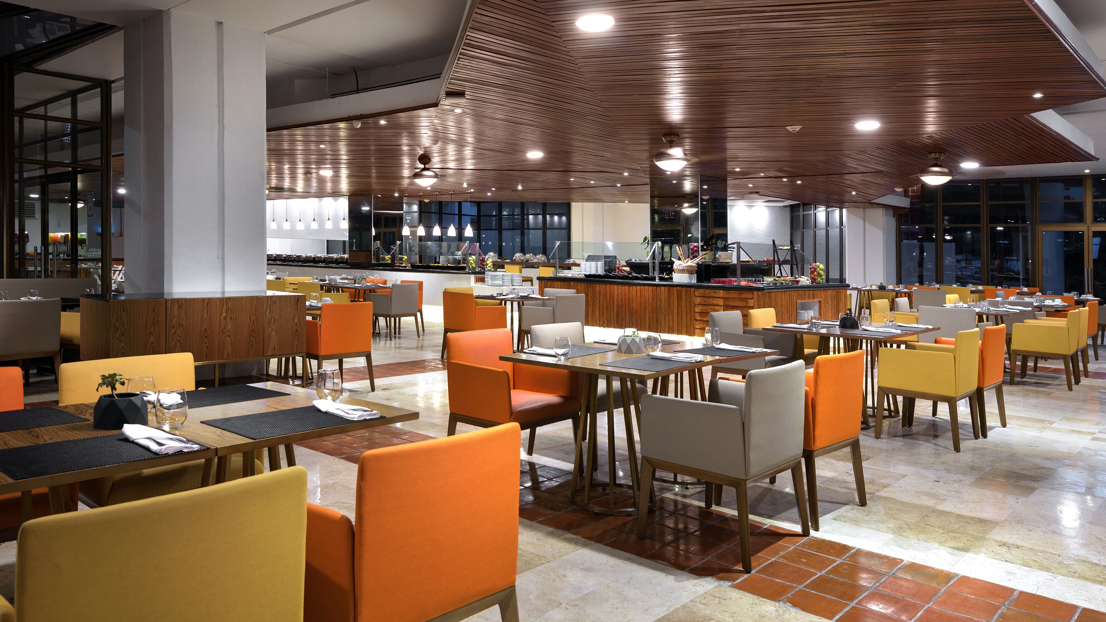 Un restaurante moderno con diversas opciones de asientos, incluyendo cabinas y mesas, y una zona de bar central.