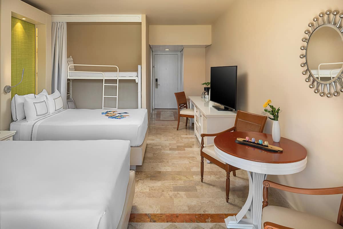 A hotel room with two beds, a TV, a desk with a chair, and a mirror on the wall.