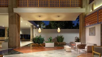 A spacious lobby with a high ceiling, large windows, and a seating area with modern furniture.