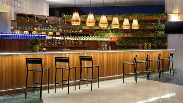 Zona de bar con mostrador de madera, múltiples lámparas colgantes y varios taburetes.