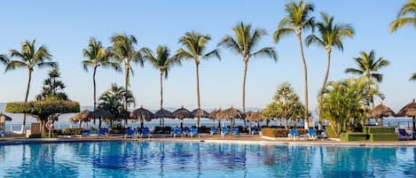 Una piscina al aire libre, sombrillas, sillones reclinables de piscina