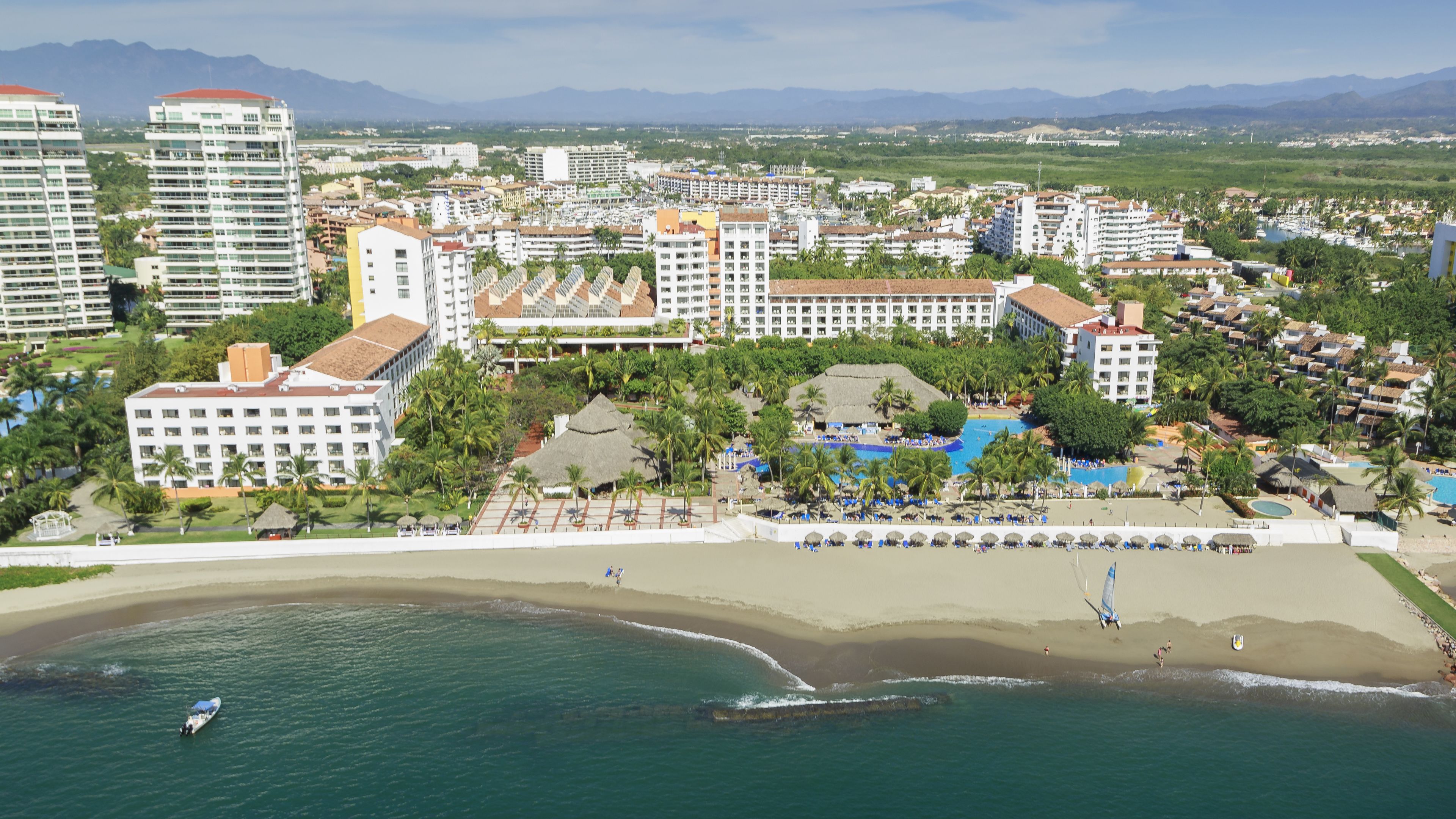 A coastal resort with multiple buildings, a beach, and a pool area.