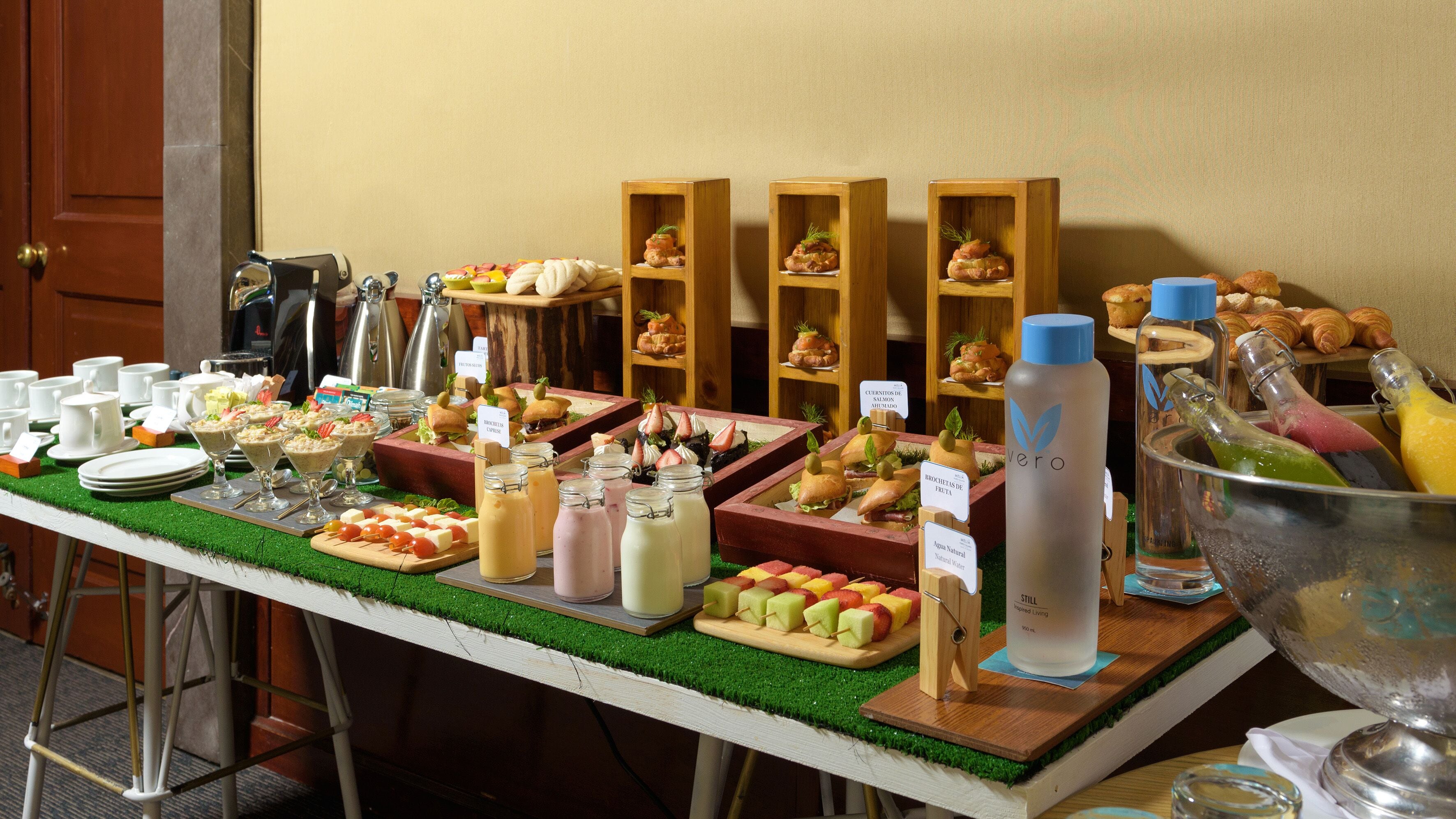 Une table de buffet proposant divers plats, notamment des sandwichs, des fruits et des boissons.