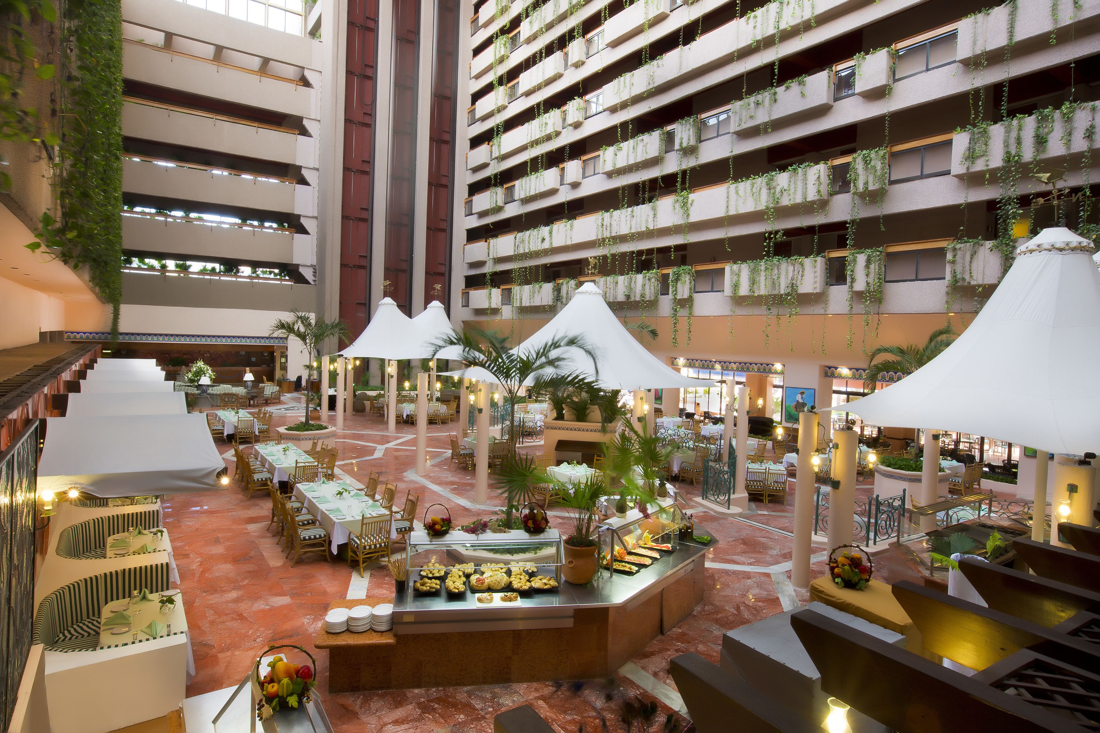 Un atrium à plusieurs niveaux comprenant des espaces de restauration, un buffet et des plantes suspendues.