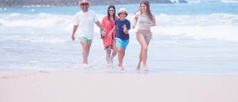 A beach scene with people walking along the shore.