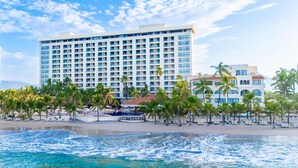 A large hotel with multiple floors and balconies, a beach with palm trees, and a view of the ocean. - Barceló Ixtapa All Inclusive (Ixtapa)