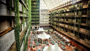 An indoor atrium with multiple dining areas, green plants on walls, and a high ceiling. - Barceló Ixtapa All Inclusive (Ixtapa)