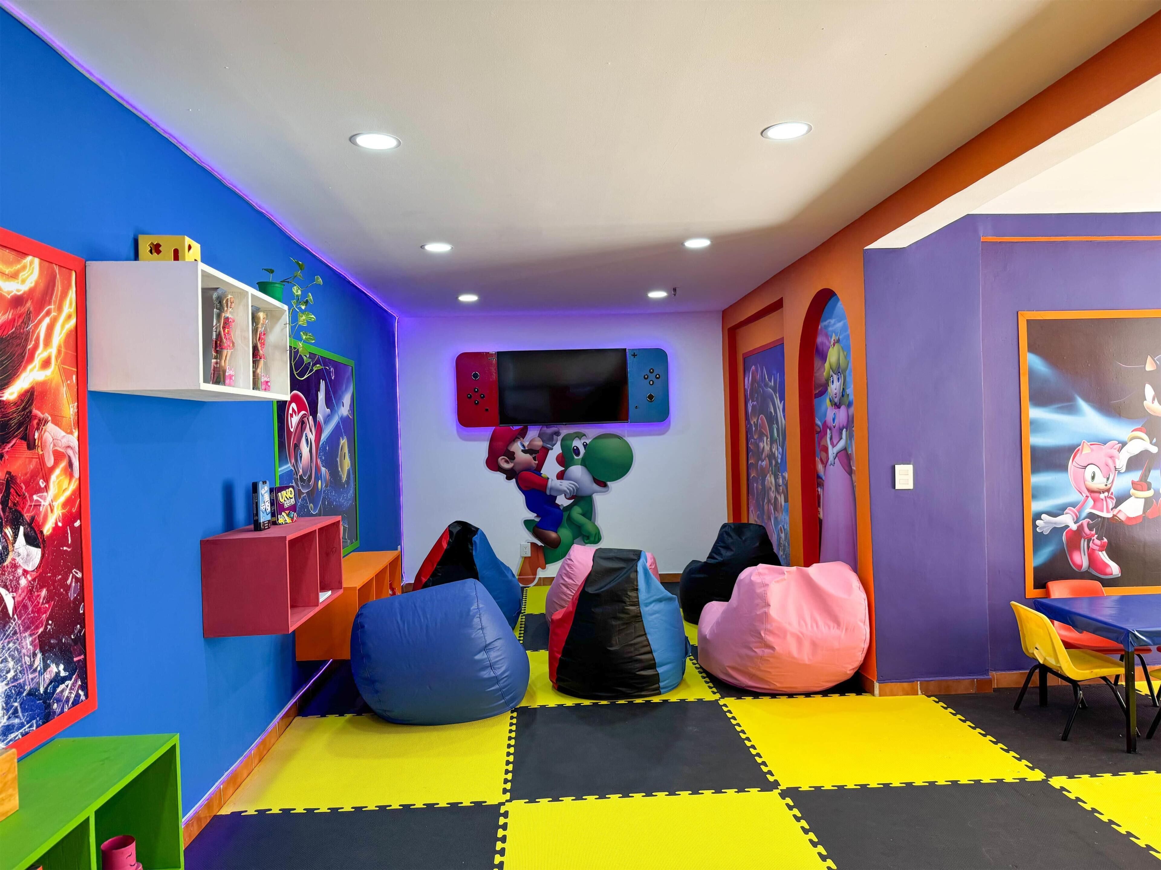 A children's playroom with colorful bean bags, a flat-screen TV, and various posters on the walls.