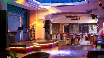 Un bar con escenario, zona de estar y equipo de DJ.