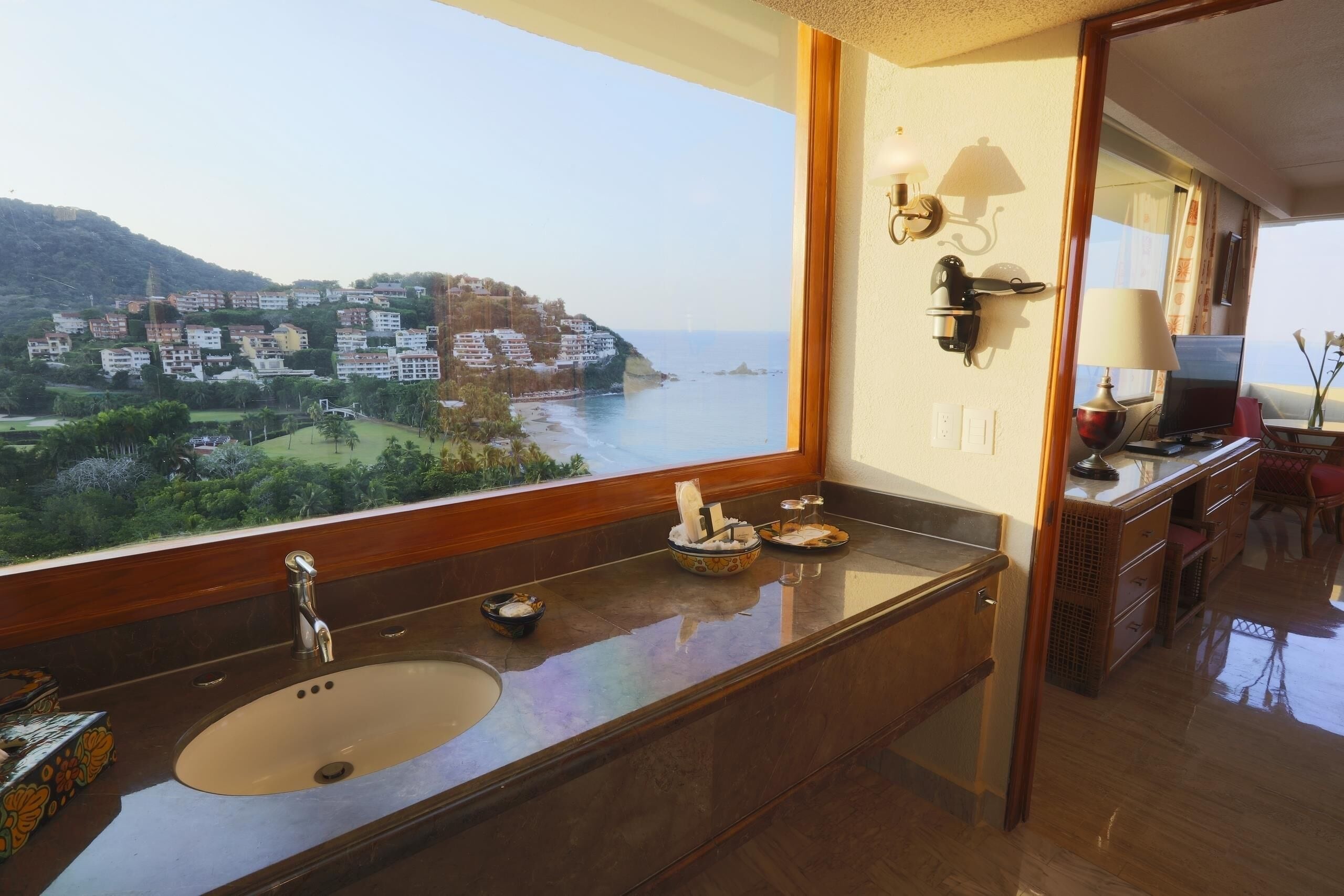 Un baño con una ventana grande, un lavamanos y un espejo.