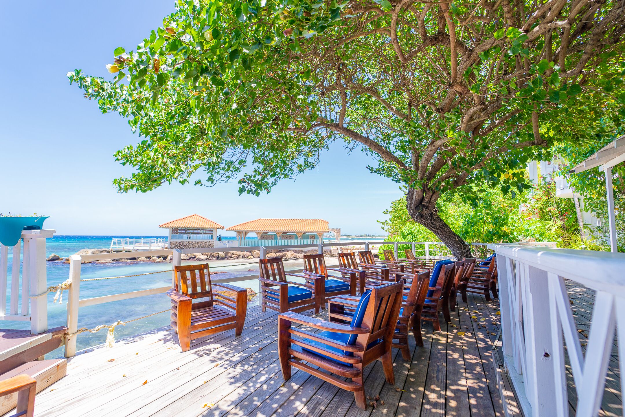 A wooden deck with outdoor seating and a view of the ocean.