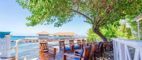 A wooden deck with outdoor seating and a view of the ocean.