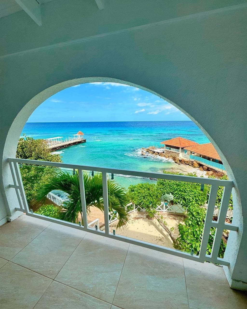 A balcony with a view of a beach and pier.